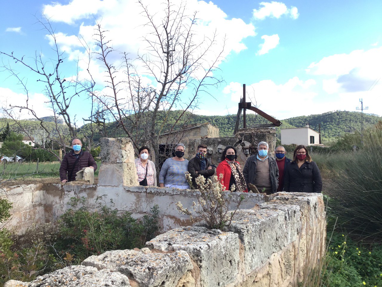 Foto de família d'autoritats i personal tècnic davant la sínia de Can Fasser